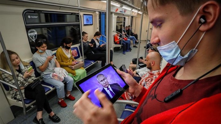 Pasajeros del metro de Moscú siguen a través de sus dispositivos móviles una intervención del presidente de Rusia, Vladímir Putin. EFE/ Yuri Kochetkov