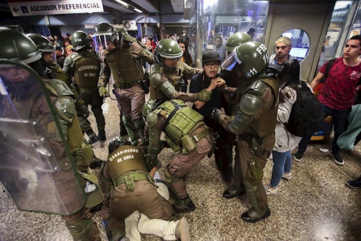 Carabineros retienen a un grupo de manifestantes en una estación del metro de Santiago en medio de una manifestación este viernes, quinto día consecutivo de protestas contra el alza del boleto. EFE/ Alberto Peña