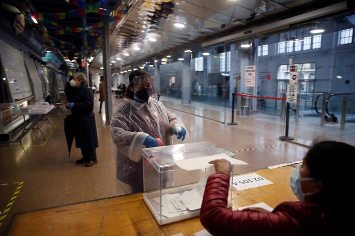 Una mujer protegida con un traje vota en el colegio electoral situado en el Mercat del Ninot en Barcelona este domingo cuando se celebran las elecciones regionales. EFE/Toni Albir