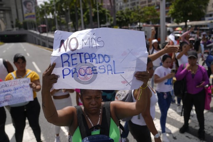 Una mujer familiar de un preso lleva un cartel contra la lentitud de los procesos judiciales en una protesta en Caracas. AP Foto/Ariana Cubillos